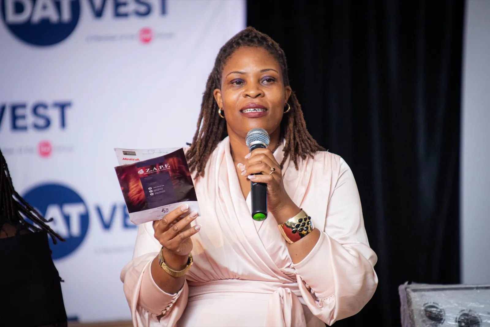 A delegate speaks into a microphone while holding the conference programme